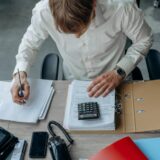 A smiling-professional reviewing documents/tax forms with calculator