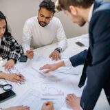 Family gathered around a table reviewing succession planning documents for their business — family succession planning 2025.