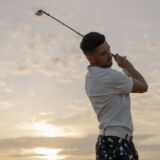 Professional golfer making a swing on a golf course, representing golfing career